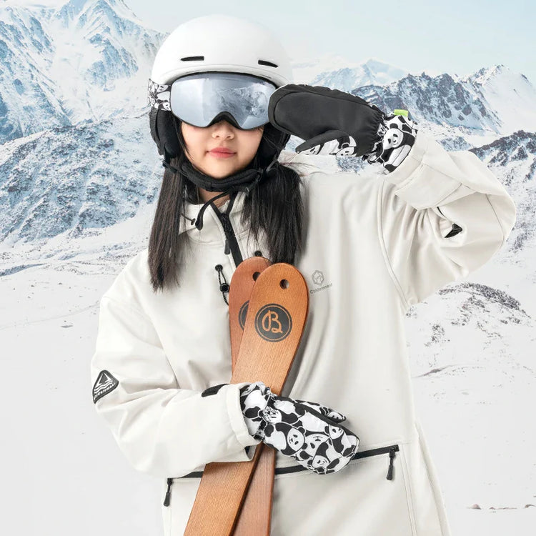 A girl wearing ski gloves holding skis in the snow