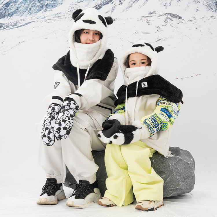 Two girls wearing panda masks and gloves sit on a rock in the snow
