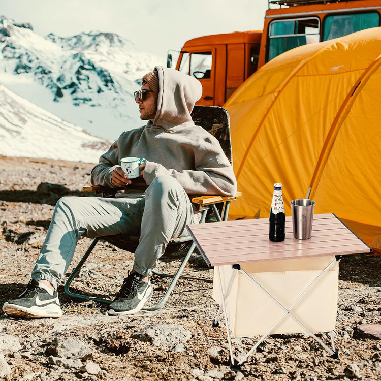 A man sits at a white  camping folding table