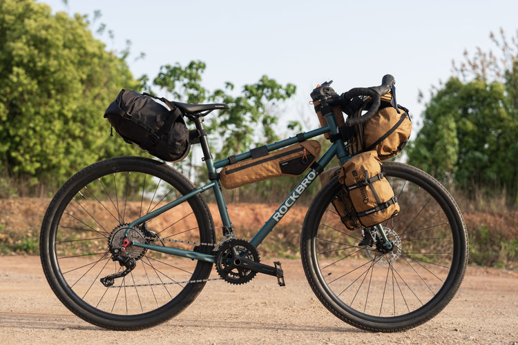 A man rides a bicycle loaded with equipment outdoors