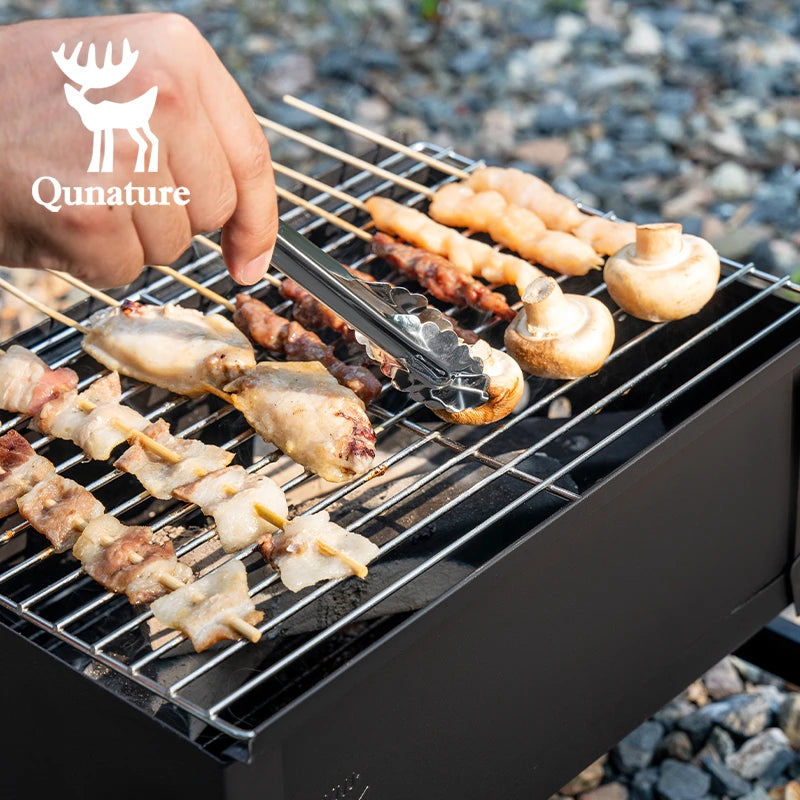 Person grilling skewered meats and vegetables on a portable grill with Qunature branding.
