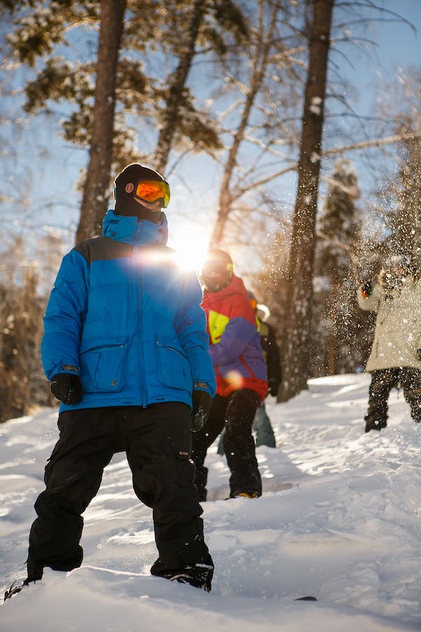A man standing in the snow with a snowboard bag