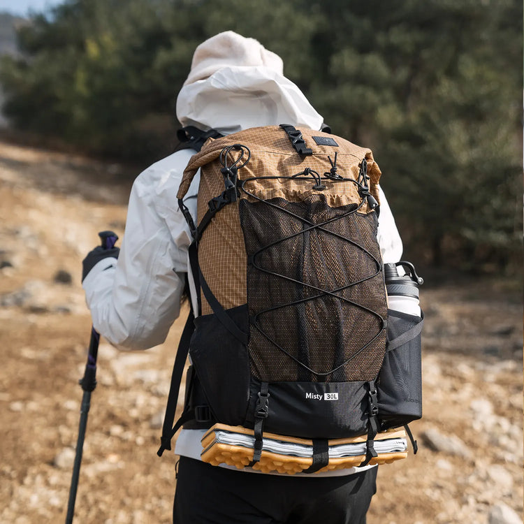 A woman with a khaki backpack and a man with a black backpack are talking while pointing into the distance