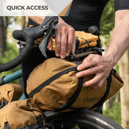 Person adjusting a brown bag on a bicycle with 'Quinault' branding, set against a natural background.