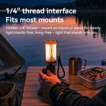 A camping lantern with a visible 1/4 inch thread interface is being held at a campsite table at dusk. White text on the image explains the thread interface feature.