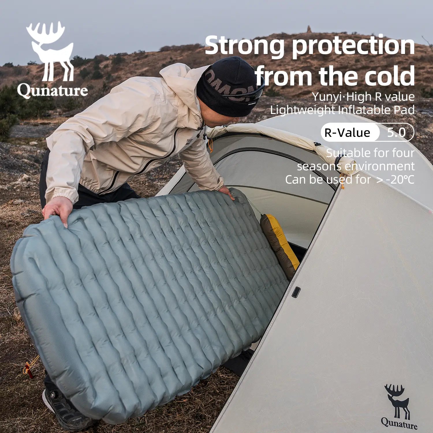 Person setting up an inflatable mattress with Quinature branding in a camping scenario.
