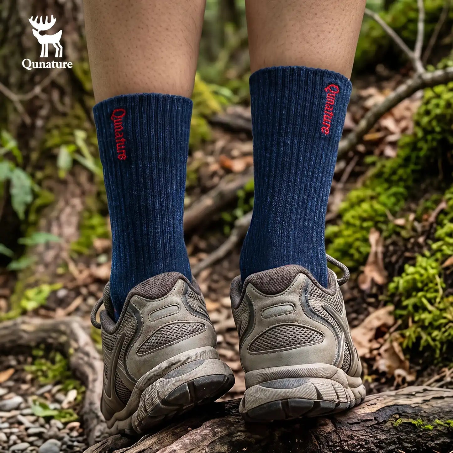 A person hiking on a forest trail wearing dark navy crew socks with red 'Qunature' branding and gray trail shoes, standing on a log with mossy ground in the background.