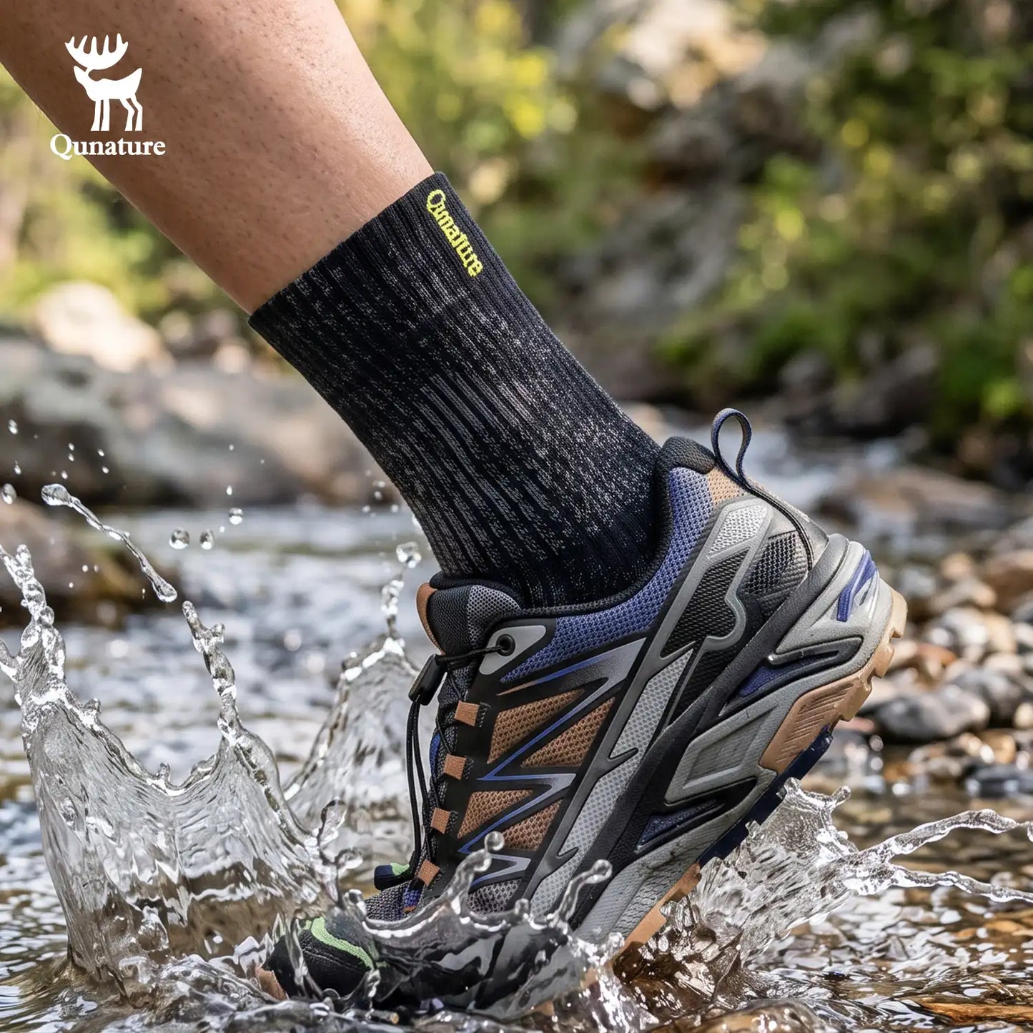 A person's foot wearing a black Qunature athletic sock and a gray, black, and blue water-resistant hiking shoe, splashing through a shallow stream outdoors. The Qunature brand logo is visible on the sock and as an overlay in the top left corner.