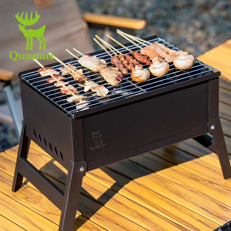 Black portable grill with skewered food on a wooden deck, featuring the Qunature brand logo.