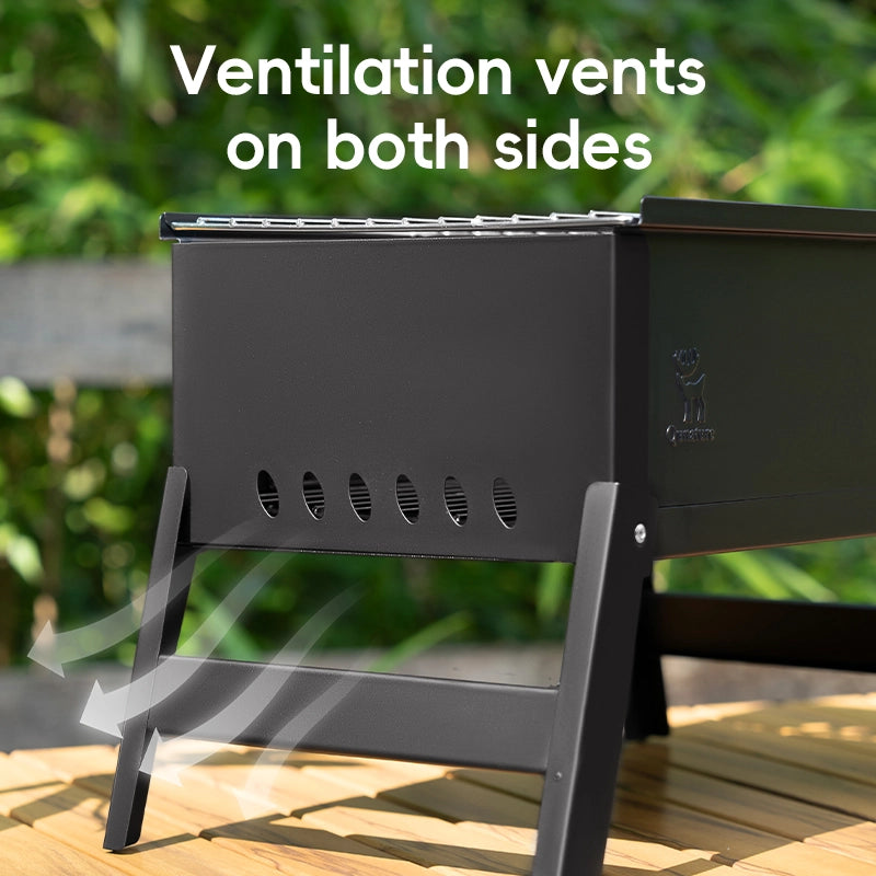 Black portable grill with ventilation vents on both sides, placed outdoors.