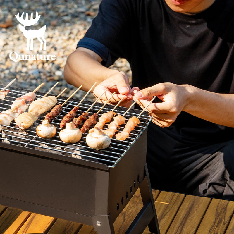 Person grilling skewered food on a portable grill with Qunature logo.
