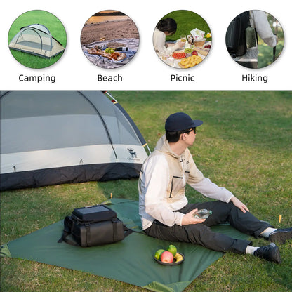 Person sitting on a green camping mat with a tent, food, and backpack in the background.