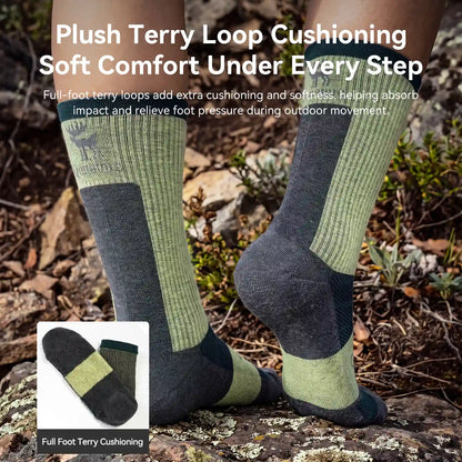 A pair of knee-high hiking socks worn on feet outdoors on rocky ground, with marketing text at the top about plush terry loop cushioning and a small inset showing the sock cross-section labeled full foot terry cushioning.