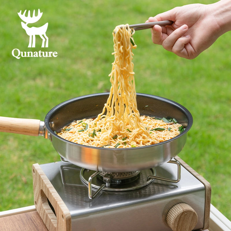 Cooking noodles outdoors on a portable stove with Qunature branding.