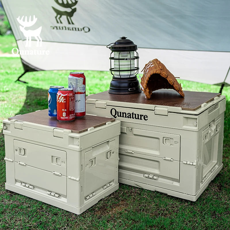 Two Qunature outdoor storage boxes with a lantern and drinks on a grassy background