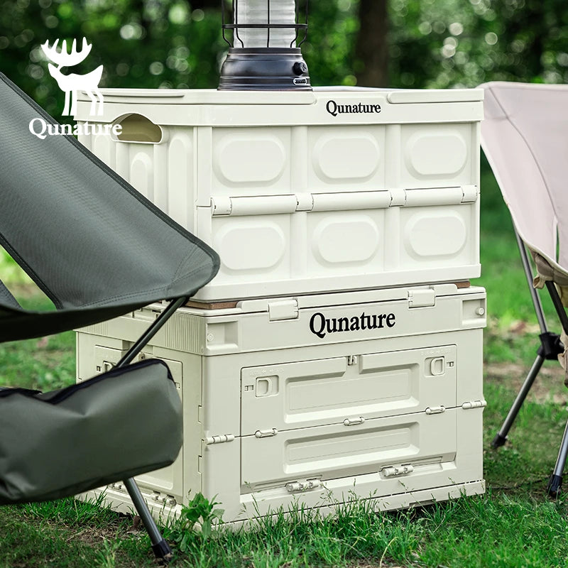 Two Qunature storage boxes stacked outdoors with camping chairs on either side.