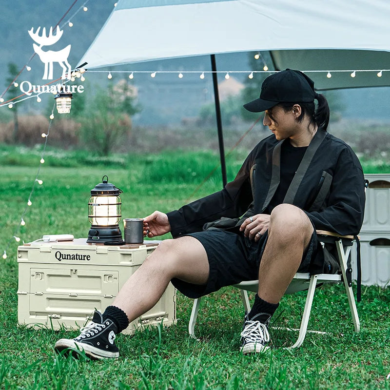 Person sitting outdoors with a lantern and Qunature branding