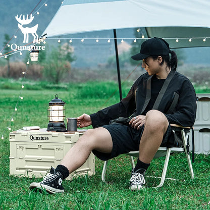 Person sitting outdoors with a lantern and Qunature branding