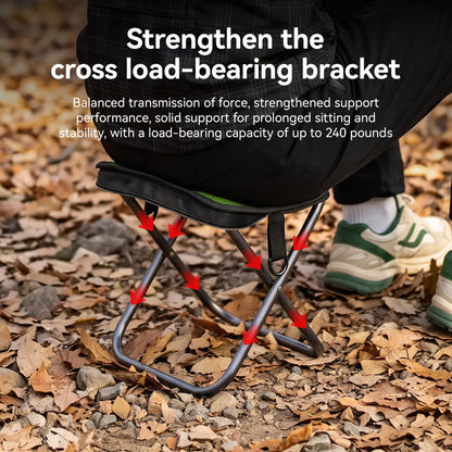 A close-up outdoor shot of a person sitting on a small folding camp stool on a ground covered with dry leaves. The image includes text reading 'Strengthen the cross load-bearing bracket' and red arrows highlighting the metal support structure of the stool.