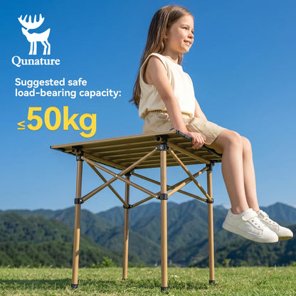 Child sitting on a portable folding table with Qunature branding and safety information against a mountainous background.