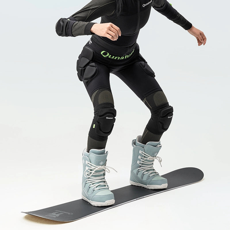 A person standing on a snowboard wearing a pair of black protective knee pads with thick sponge