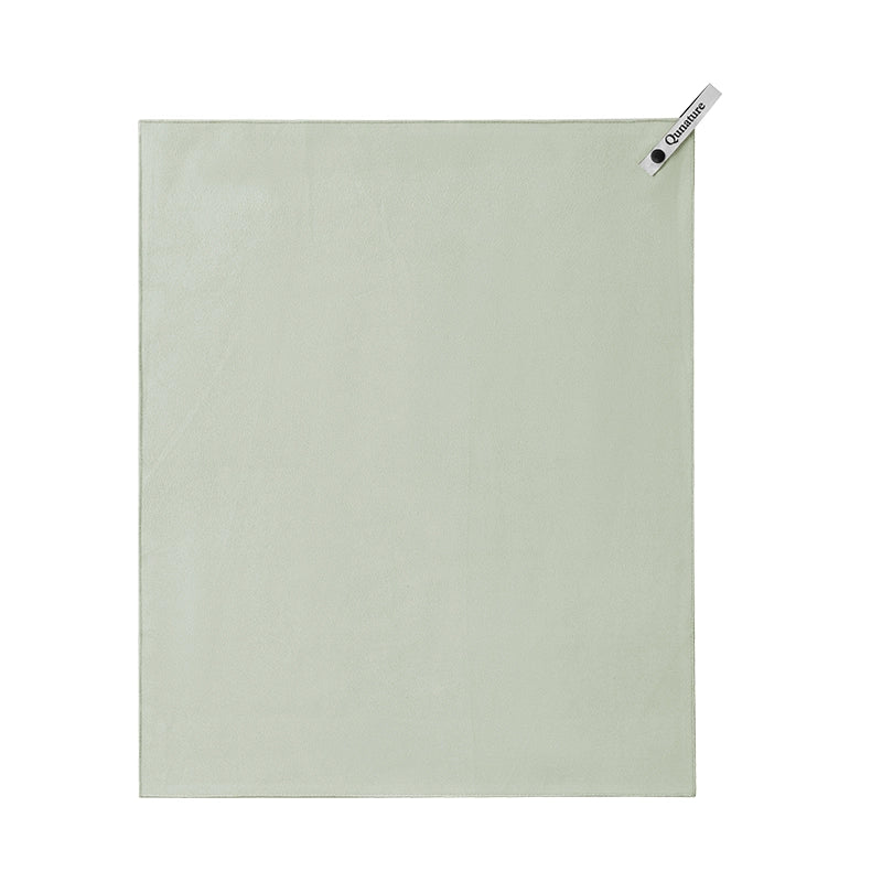 A light sage green rectangular towel or cloth with a small white brand tag in the top-right corner, shown flat against a plain white background.