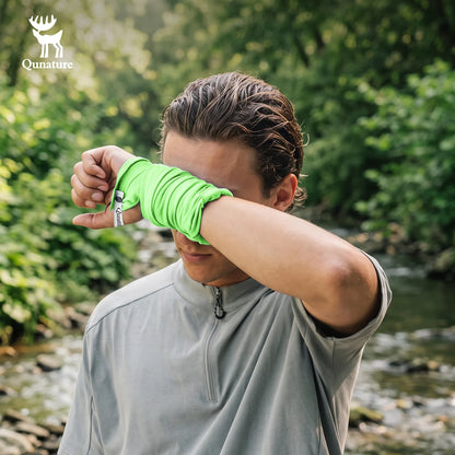 A man outdoors by a stream wearing a bright neon green wrap-around wrist/forearm sleeve over a light gray athletic quarter-zip top. The Qunature brand logo is visible in the top-left corner.
