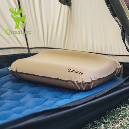 Inflatable camping pillow on a blue sleeping pad inside a tent with Qunature branding.