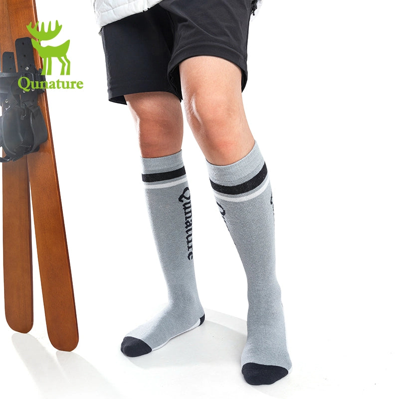 A person wearing grey long ski socks with lettering
