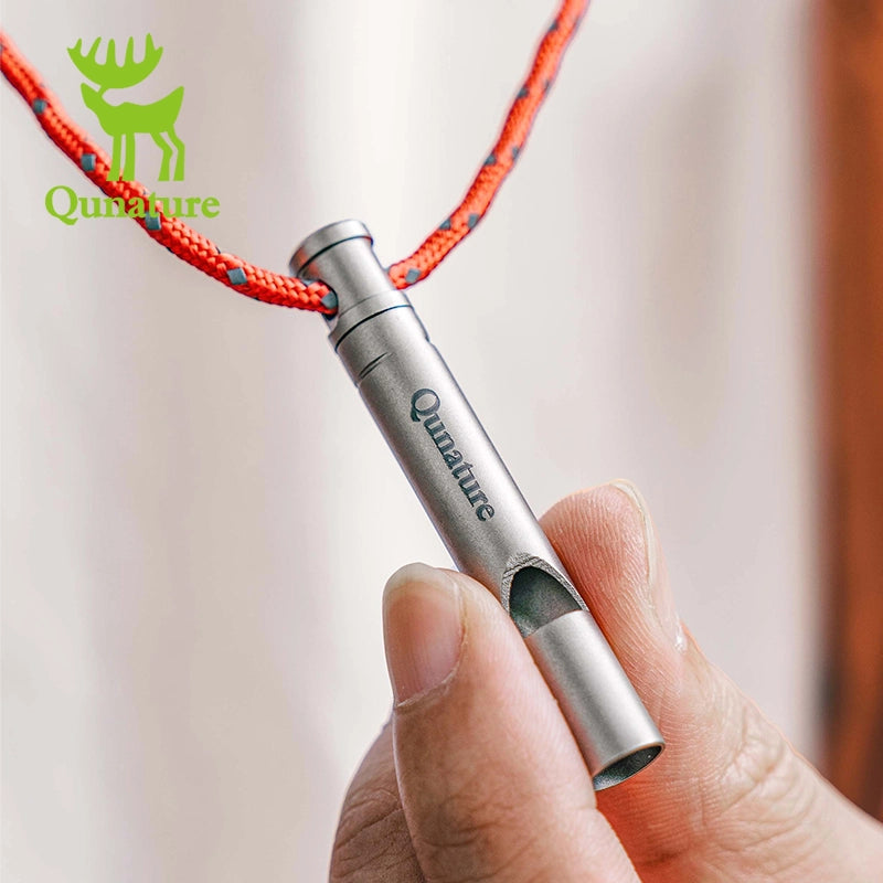 Metal whistle with red rope handle held by a hand, Qunature brand visible