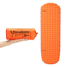Orange inflatable sleeping pad with packaging held by a hand on a white background