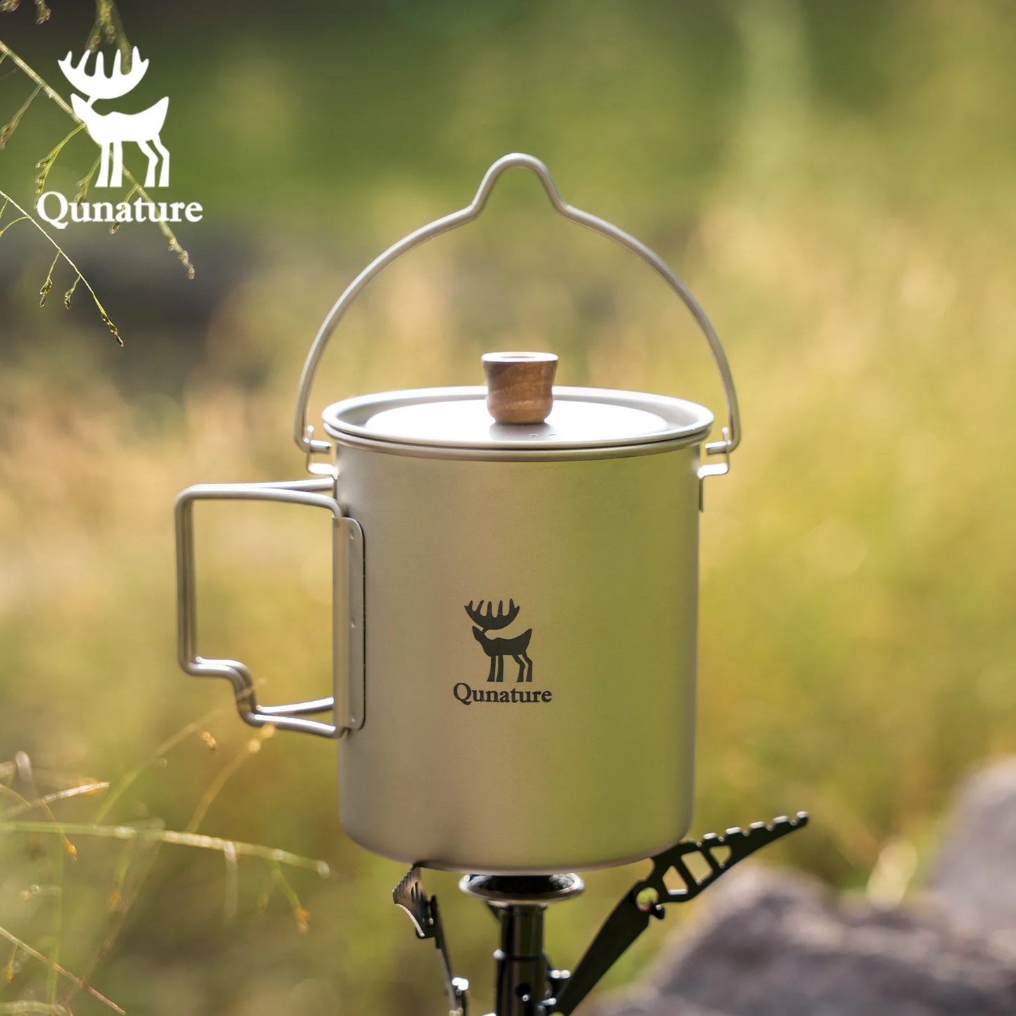 Camping mug with handle on a stand against a natural background, featuring Qunature logo.