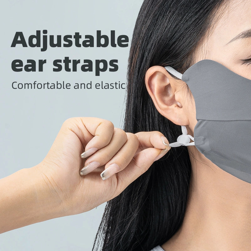 Person adjusting a gray face mask with adjustable ear straps on a light gray background