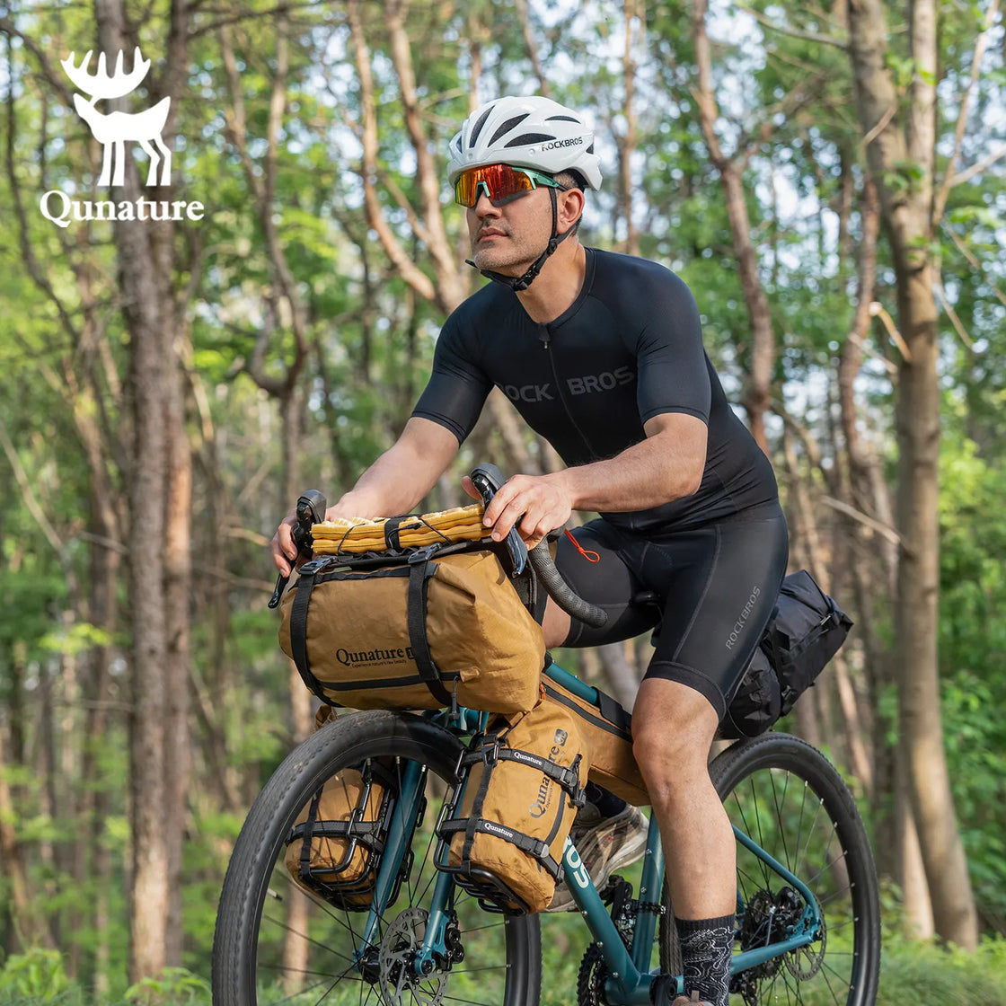 A man is riding a bicycle outdoors with many bike bags installed on it