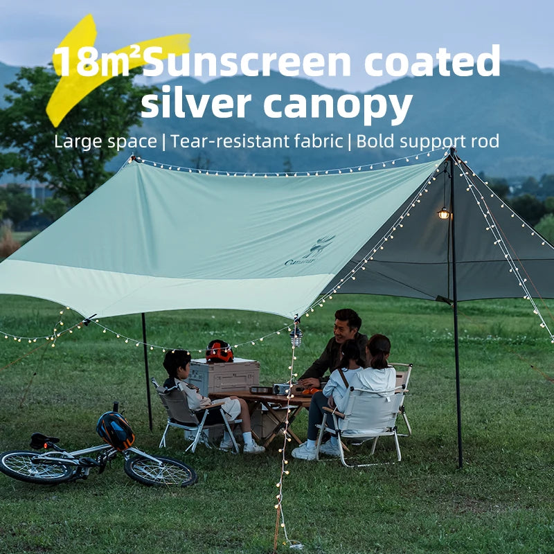 18m” Sunscreen coated silver canopy with people sitting under it in a grassy area.