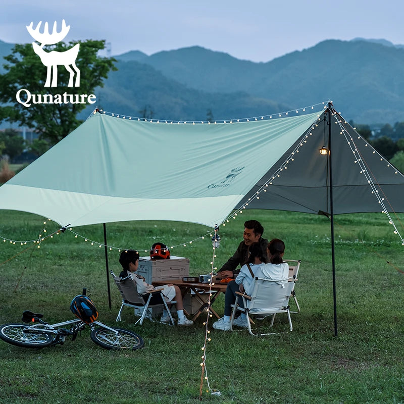 Family camping under a Qunature tent with mountains in the background