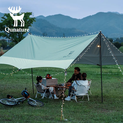 Family camping under a Qunature tent with mountains in the background
