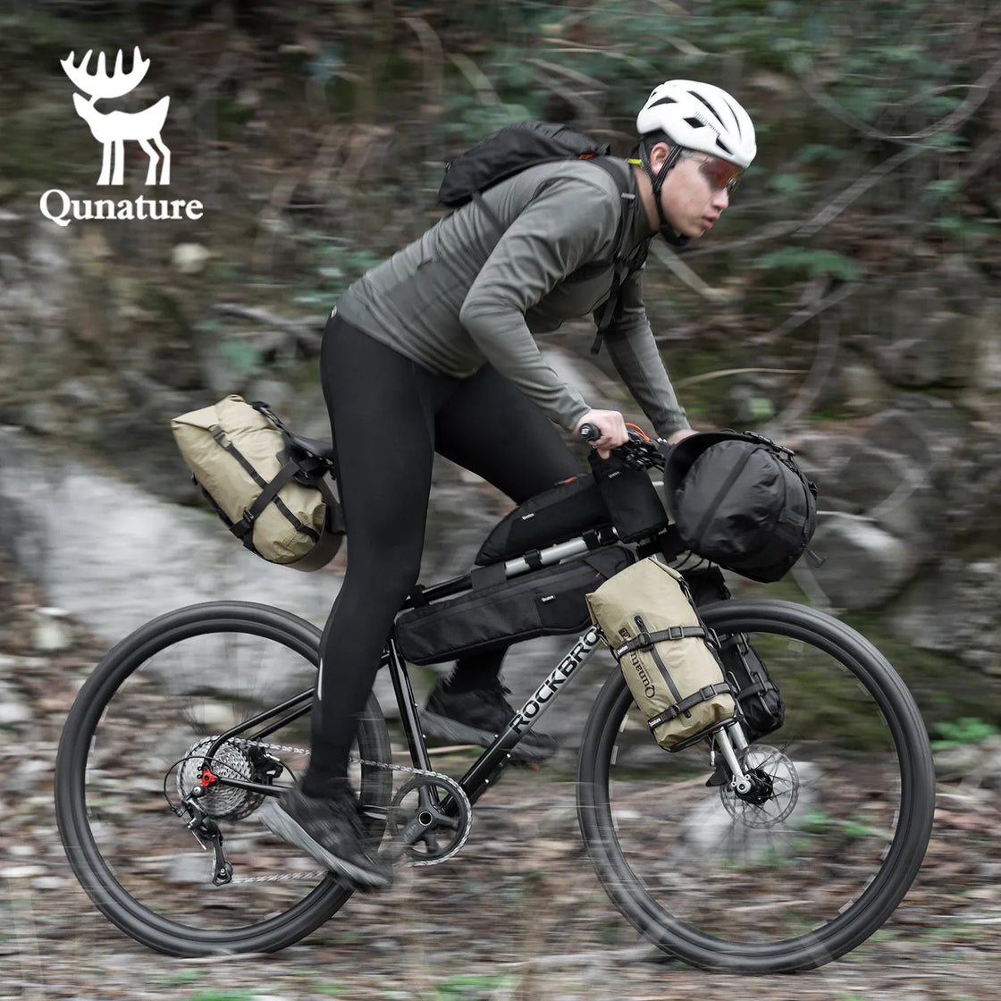 A boy is riding a bicycle outdoors with a black waterproof compression bag and many other bike bags