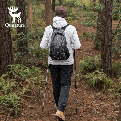 Person hiking in a forest with a black backpack.