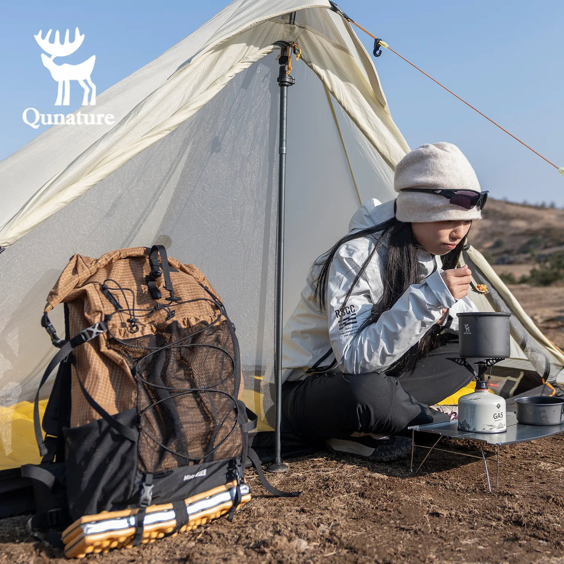 A khaki hiking backpack was placed on the ground, and a girl was sitting in a tent next to it eating.