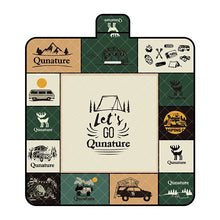 A Qunature branded outdoor picnic mat with a patterned design featuring elements like mountains, trees, and camping gear, in green, beige, and other colors.