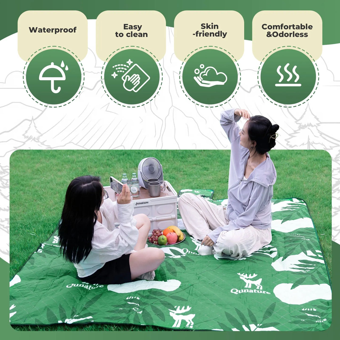 Two people sitting on a green picnic blanket with a Quinature brand logo, surrounded by icons indicating product features.