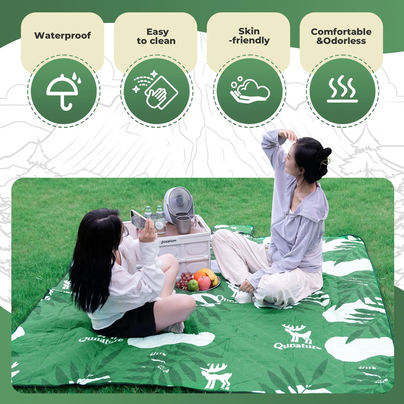 Two people sitting on a green picnic blanket with a Quinature brand logo, surrounded by icons indicating product features.