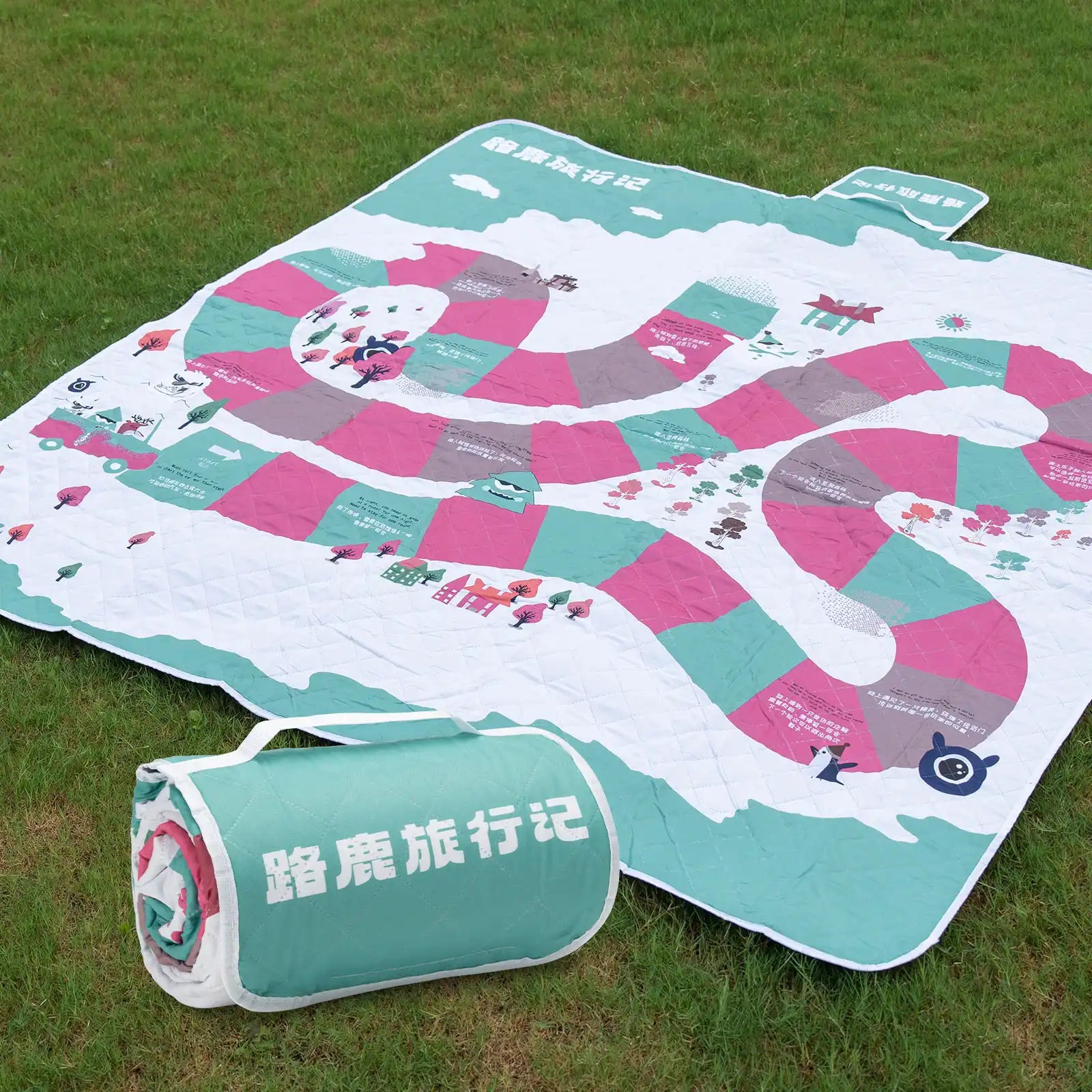 A Qunature branded outdoor picnic mat with a patterned design featuring elements like mountains, trees, and camping gear, in green, beige, and other colors.