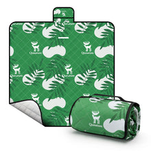 A Qunature branded outdoor picnic mat with a patterned design featuring elements like mountains, trees, and camping gear, in green, beige, and other colors.