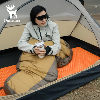 Person sitting inside a tent holding a coffee cup, with Qunature branding visible.